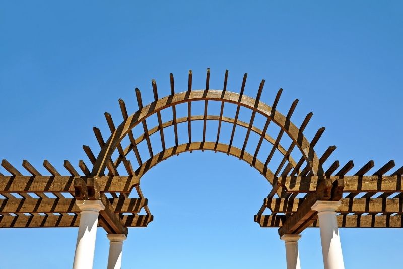 arc design pergola made of wood material in a clear blue sky
