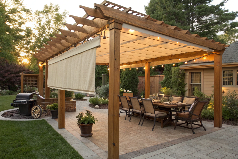 Wooden pergola with retractable shade cloth covering outdoor dining and barbecue entertaining area